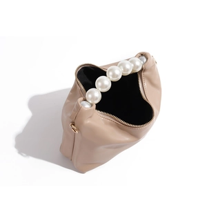 Close-up of pearl handle and zipper closure on the soft pleated beige dumpling bag