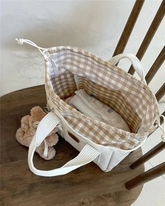 Detail of baby tote bag featuring bear embroidery and drawstring plaid lining closure