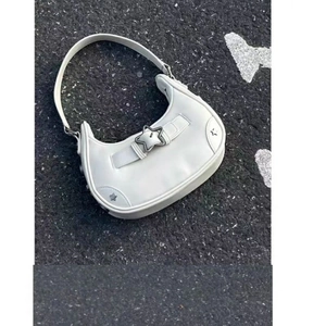 Détail d'un sac hobo en cuir blanc avec boucle en métal en forme d'étoile sur l'asphalte