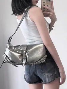 Detail of silver metallic shoulder bag featuring Y2K buckle and adjustable side strap