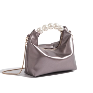 Detail of silver metallic mirror clutch with pearl handle and golden chain strap