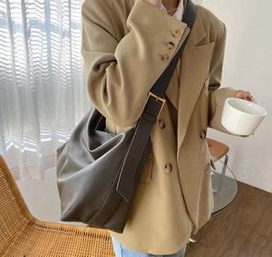 Detail of soft brown leather hobo bag with adjustable wide strap and golden buckle