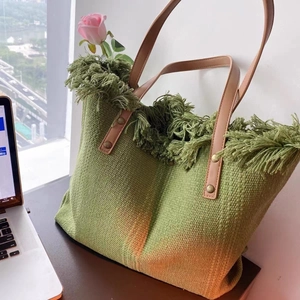 Detail of forest green knit tote with fringe trim and brown leather handles