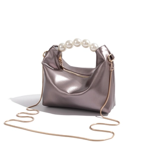 Close-up of metallic silver dumpling bag with large pearl handle and gold chain strap