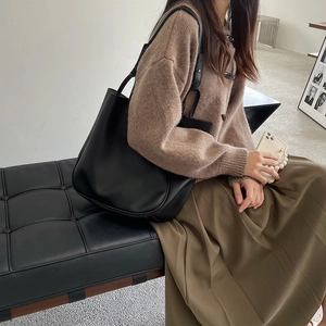 Modern black matte leather tote bag worn by a model in a minimalist indoor setting
