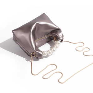 Detail of champagne silver pleated pouch with large pearl handle and gold snake chain