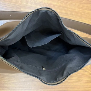 Interior view of large brown shoulder bag featuring black lining and zipper pockets