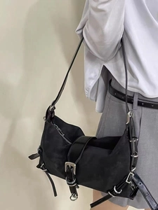 Detail of black utility shoulder bag featuring metallic buckles and industrial straps