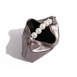 Detailed view of metallic purple dumpling bag with large pearl handle and golden zipper