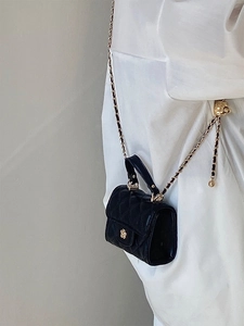 Dettaglio mini borsa trapuntata nera con fibbia a fiore di camelia dorata e tracolla
