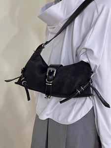 Detail of matte black shoulder bag featuring adjustable silver metal buckles and straps