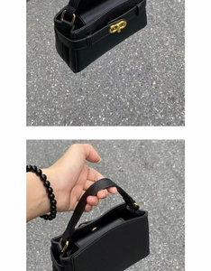 Close-up of black litchi grain leather bag with gold twist lock and top handle detail