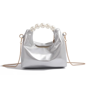 Detail of silver metallic dumpling bag featuring pearl top handle and gold chain strap