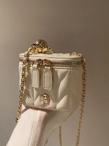 Detailed view of quilted leather box bag with gold floral logo and adjustable chain strap