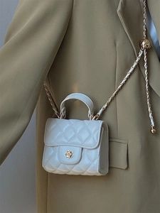 Dettaglio della mini borsa trapuntata bianca con chiusura a camelia dorata su abito
