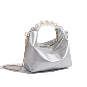 Detail of silver metallic leather handbag with large pearl handle and gold chain strap