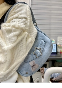 Détail du sac à bandoulière en jean bleu clair avec boucle étoile et motif ours