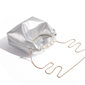Detail shot of silver metallic dumpling bag with large pearl handle and gold chain