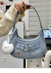 Détail du sac croissant en denim bleu avec boucle étoile, écusson ours et cœur doux