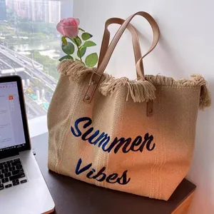 Detail of straw tote bag with Summer Vibes embroidery and stylish fringe trim