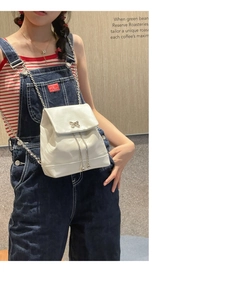 Mini sac à dos argenté avec chaîne et boucle papillon porté par un mannequin femme