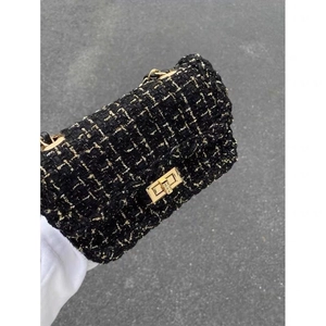 Detail of black houndstooth tweed shoulder bag with gold metallic chain strap