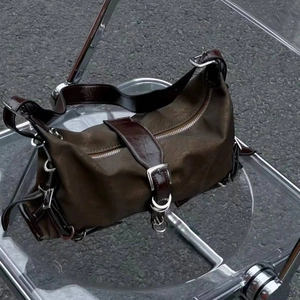 Detail of dark brown industrial shoulder bag with leather trim and silver buckles