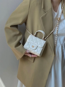 Dettaglio mini borsa bianca trapuntata con chiusura a camelia dorata e tracolla