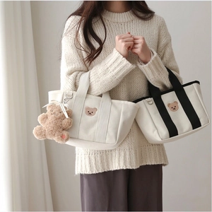 Detail of canvas tote bags with bear embroidery in cream and black contrast colors