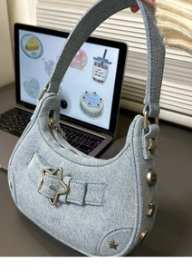Détail du sac hobo en jean bleu clair avec boucle métallique en étoile et détails de rivets