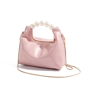 Close-up of elegant pearl handle detail and glossy light pink patent leather handbag