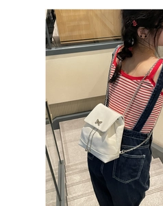 Vue détaillée du sac à dos blanc matelassé à chaîne avec fermoir papillon en métal