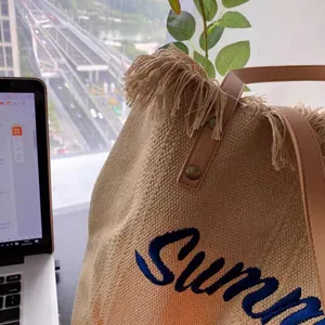 Detail of Summer embroidery and beige fringe texture on woven tote bag with leather handles