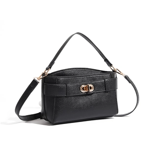 Close-up of black litchi texture leather with a gold oval turn-lock on the shoulder bag