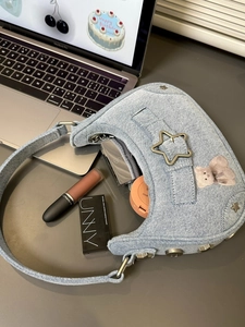 Détail du sac à bandoulière en denim bleu clair avec boucle étoile et texture tricot