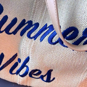Detailed macro view of Summer Vibes blue chenille embroidery on woven tote bag fabric