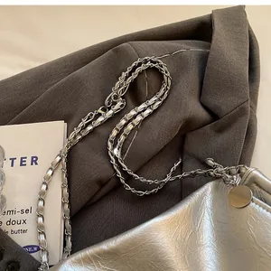 Detail view of the silver metallic shoulder bag showing chain strap and textured leather