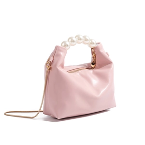 Close-up of pink leather pearl handbag with heart pendant and gold chain strap