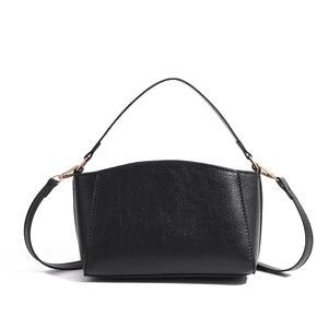 Close-up of black lychee texture leather bag with elegant gold metal buckle and hardware