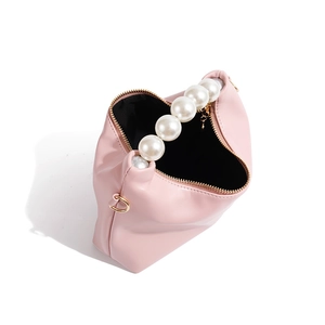 Detail view of pink dumpling bag with elegant oversized pearl handle and gold zipper