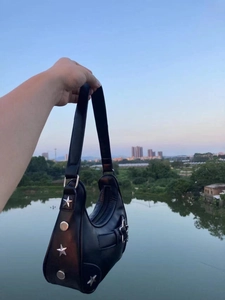 Détail de clous étoiles argentés et boucle sur un sac vintage noir porté épaule