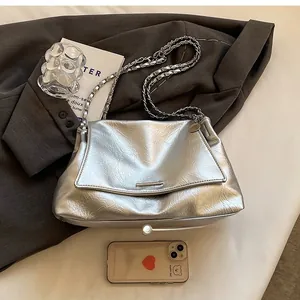 Silver metallic chain bag shown next to a smartphone for detailed size comparison