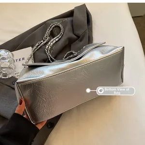 Detail view of the silver metallic tote bag bottom with stylish metal chain strap