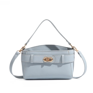 Detail of light blue lychee pattern leather handbag with golden double rotary buckle