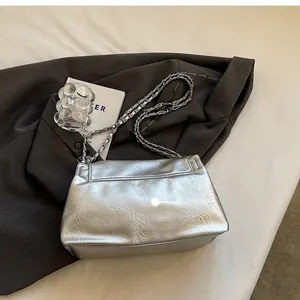 Close-up of silver chain strap on a metallic textured shoulder bag with soft folds