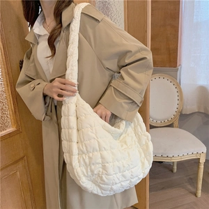 Minimalist off-white quilted cloud bag shown on shoulder in a soft lifestyle setting