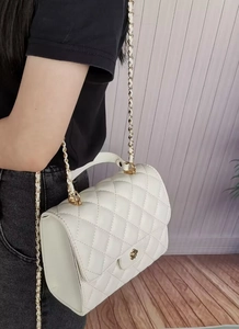 Dettaglio borsa a tracolla trapuntata beige con manico in metallo dorato e chiusura