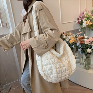 Close-up of a white quilted hobo bag being worn by a model in a natural indoor setting