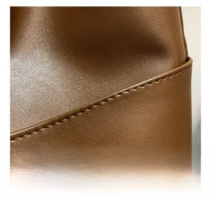 Detail of the high-quality stitching on a brown leather tote bag with fine texture