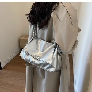Detail of silver metallic leather chain bag with crinkled texture on a model